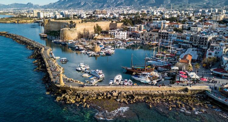 Aerial view of Kyrenia harbor with medieval castle walls, moored yachts and turquoise Mediterranean waters.