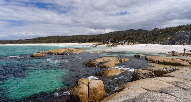Littoral rocheux avec des bassins de marée contrastés turquoise et sombres par une journée partiellement nuageuse