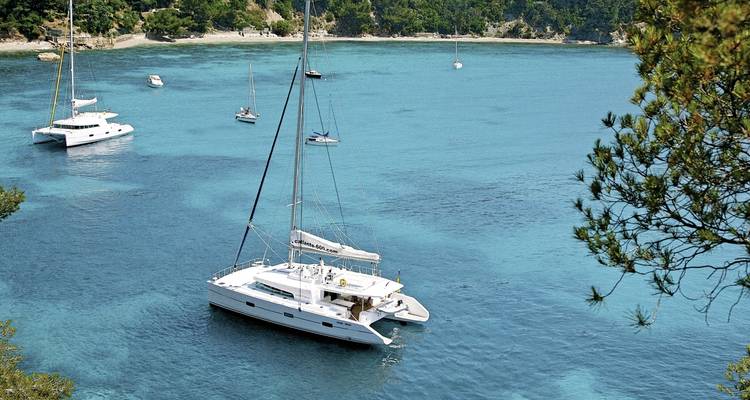 Anchored yachts in a serene bay with clear waters.