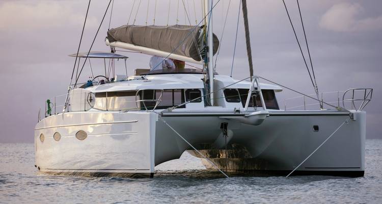 Catamaran sailing in calm waters with sunset skies.