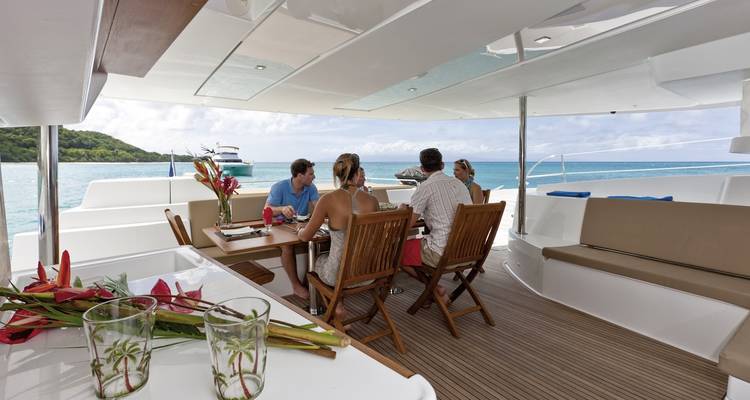 Group dining on yacht deck with ocean view.