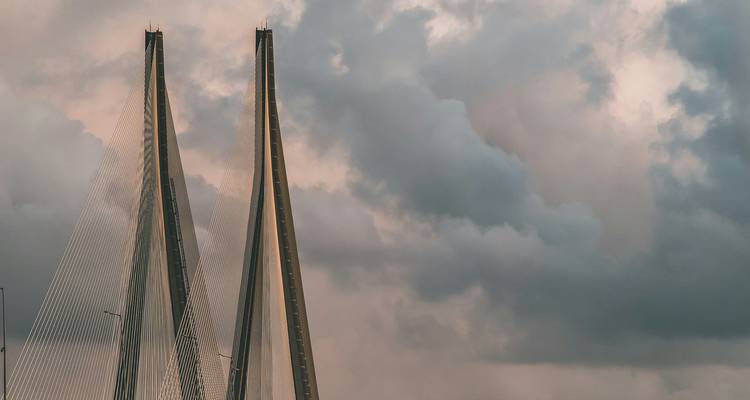 Primer plano de los dos pilares gemelos del puente Sea Link atravesando nubes oscuras y dramáticas.