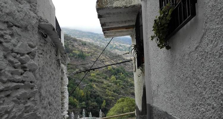 Ruelle étroite entre des bâtiments blanchis à la chaux avec vue sur la vallée.