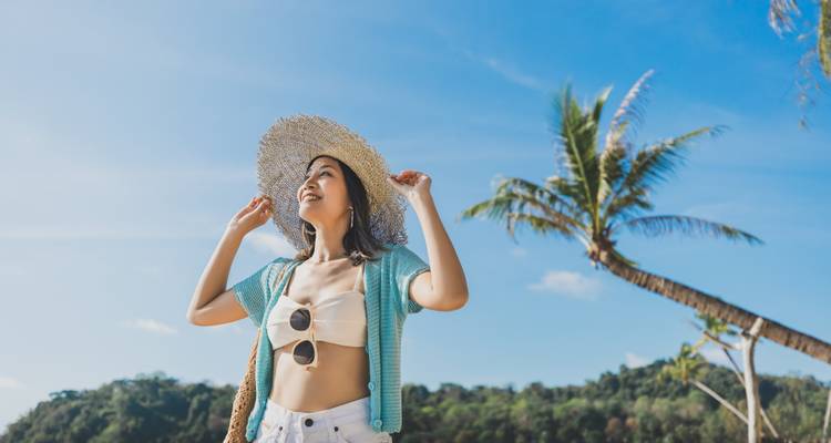 Een vrouw die geniet van het strand met een palmboom op de achtergrond.