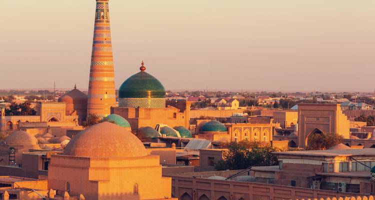 Warm sunset light bathes Khiva’s skyline with its striped Islam Khodja minaret and domes.