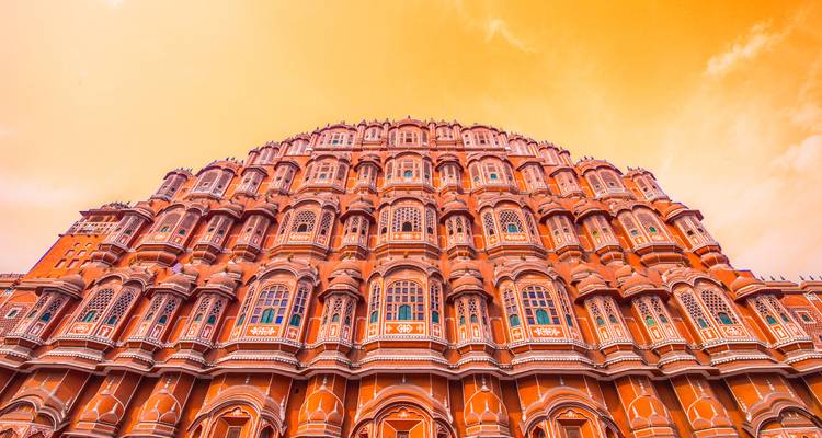 Looking up at the Hawa Mahal against a vibrant orange sky.