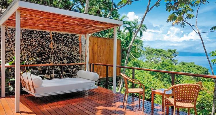 Sitzbereich im Freien mit Blick auf das Meer und üppige Vegetation.