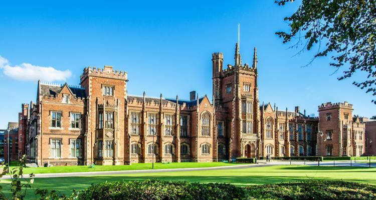 A grand university building with a large lawn.