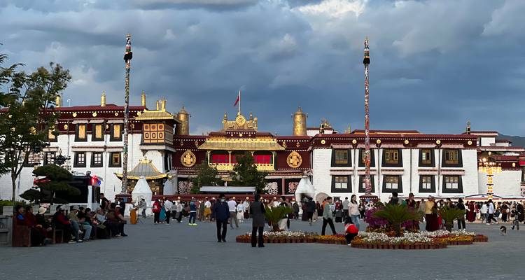 People gathered in front of a large, ornate building with golden and red decorations.