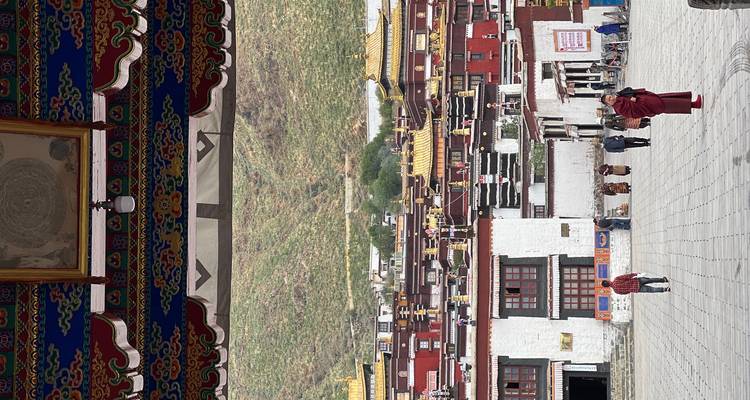People walking in a courtyard with traditional Tibetan architecture.