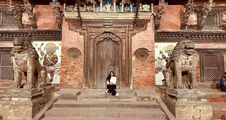 Person, die zwischen verzierten Steinlöwen in einem Tempel sitzt.