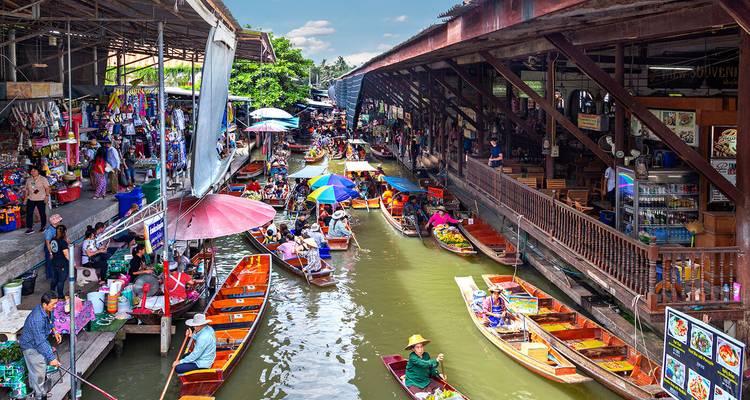 Bunter schwimmender Markt mit Booten und Sonnenschirmen.