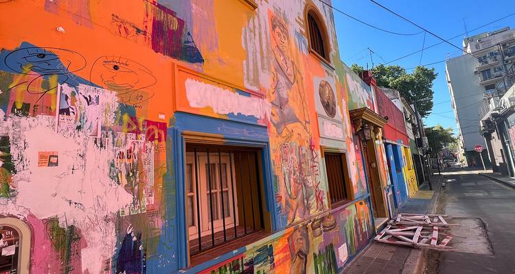 Rue urbaine étroite bordée de murales aux couleurs vives et de façades colorées sous une lumière du jour éclatante.