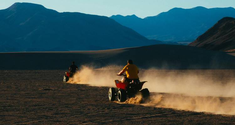 Deux personnes conduisant des VTT dans un paysage désertique.