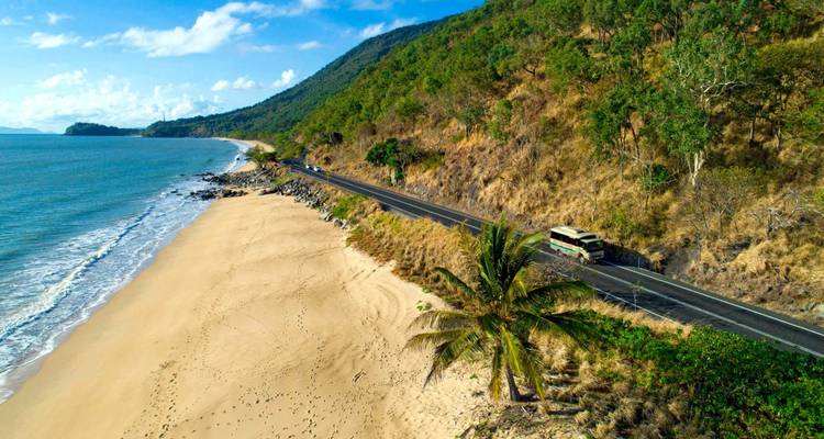 Küstenstraße mit Autos parallel zu einem Strand.