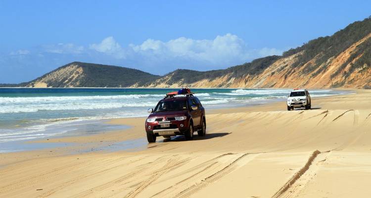 Fahrzeuge, die auf einem sandigen Strand fahren.