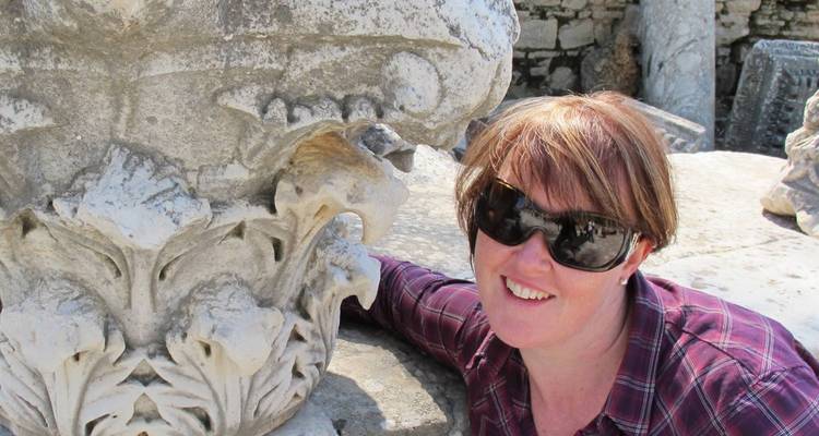 Person posing with an ornate stone carving.