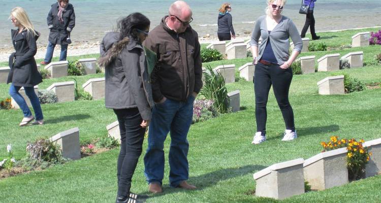 Several people visiting a cemetery near water.