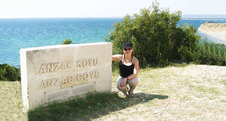 Person posing by a stone with Anzac Cove inscription.