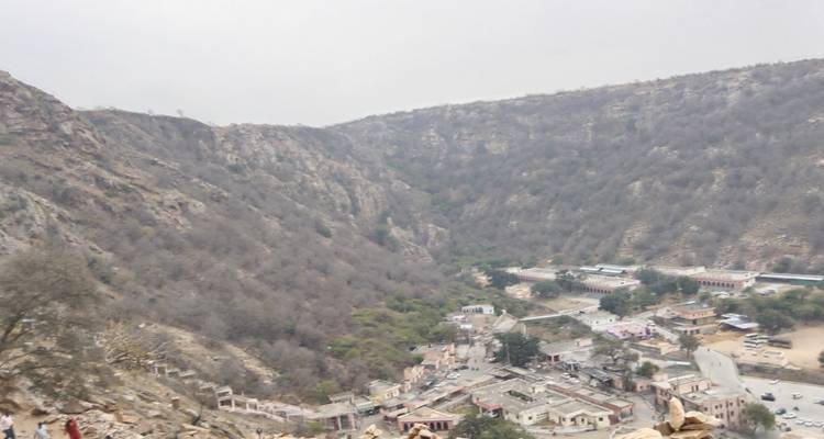 Panoramic overlook of valley town nestled between barren hills beneath grey sky.