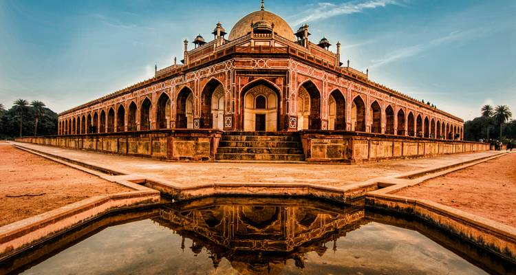 Symmetrical view of Humayun’s Tomb reflected perfectly in a foreground pool under warm evening light.