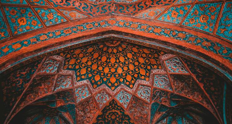 Vibrant, ornate ceiling of a Mughal archway showcasing intricate geometric and floral mosaic.