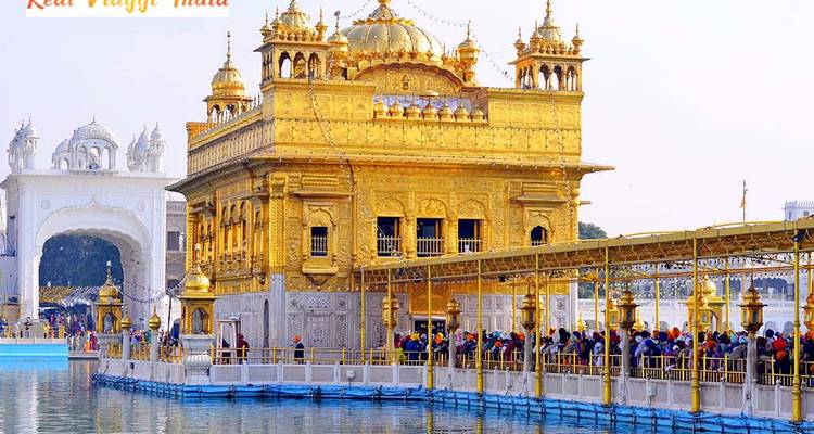Golden temple with people on the bridge in front of it.