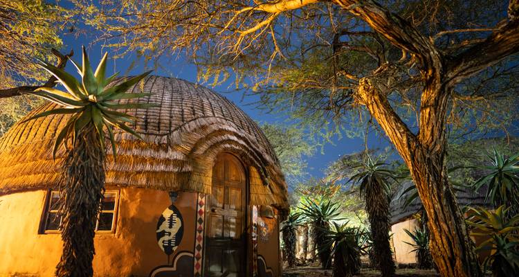 Cabaña africana tradicional bajo un árbol por la noche.