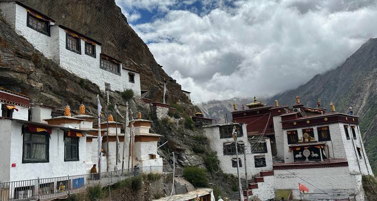 Bâtiments traditionnels construits à flanc de montagne sous un ciel nuageux.