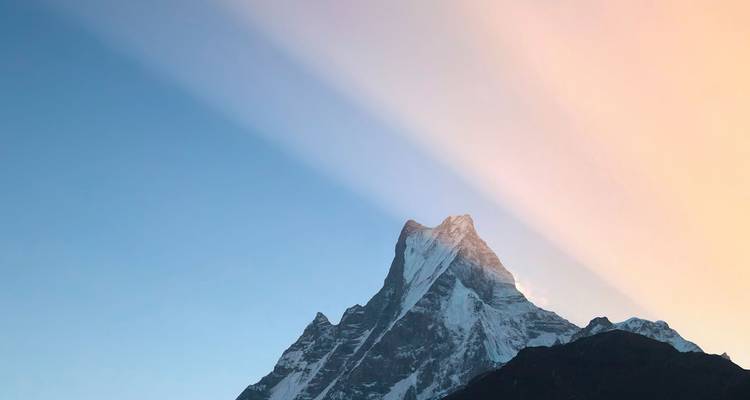 Dramatic peak of Machhapuchhare catching warm dawn light against clear sky