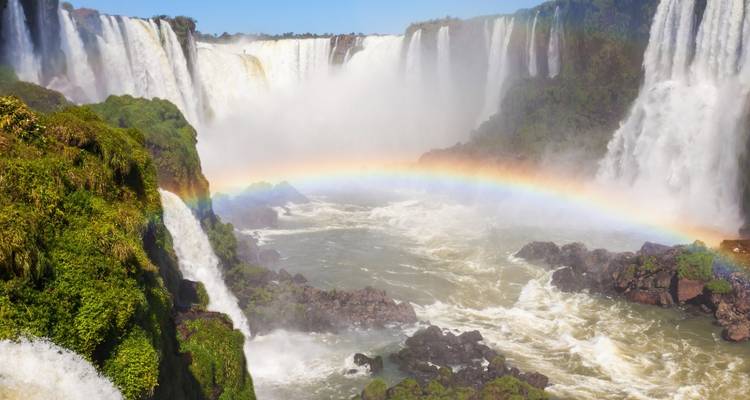 Wide waterfalls with a visible rainbow over the water.