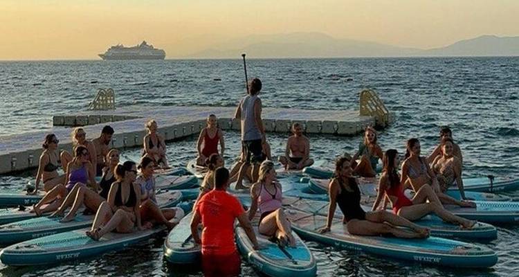 People on paddleboards in the water, cruise ship and mountains in background.