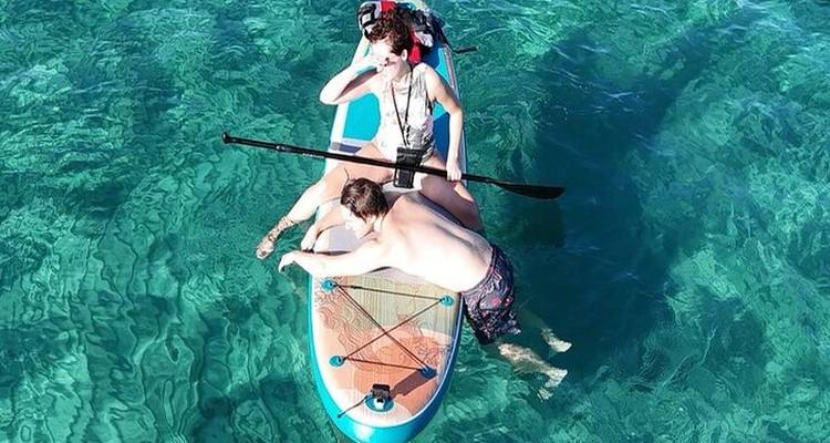 Two people on a paddleboard in clear ocean water.