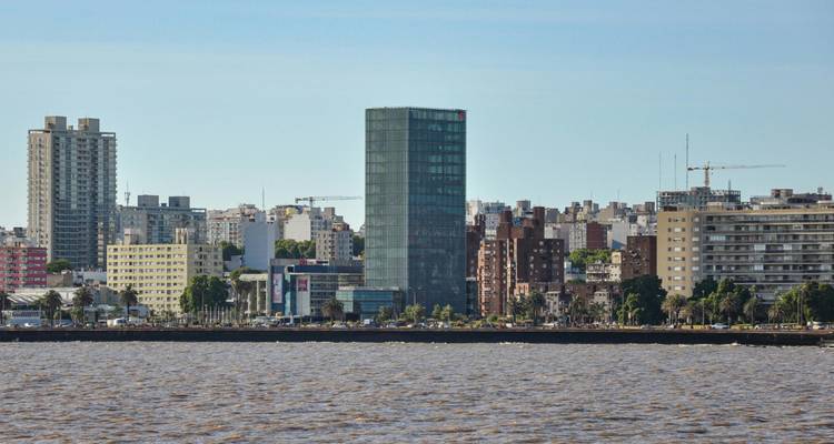 Montevideo waterkant skyline bekeken over golvend bruin rivierwater onder heldere hemel