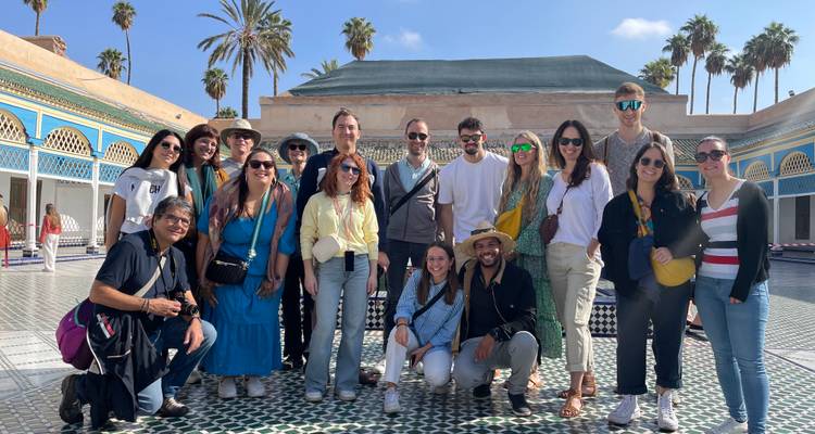 Grupo de personas posando en un patio con palmeras de fondo.