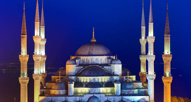 Beleuchtete Moschee vor einem Nachthimmel.