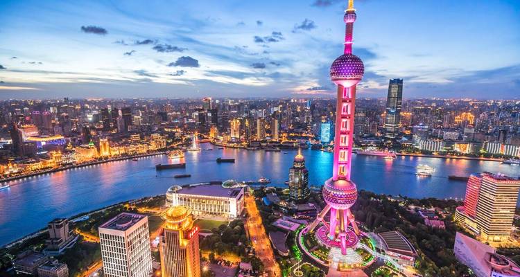 Nächtliche Luftaufnahme von Shanghais Skyline in Pudong, dominiert vom hell erleuchteten Oriental Pearl Tower neben dem Huangpu River.