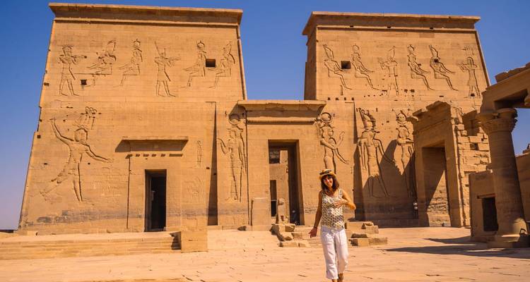 Woman in front of ancient Egyptian temple featuring hieroglyphics.