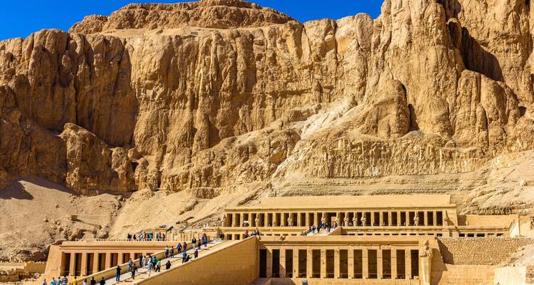 Tempel van Hatshepsut genesteld onder torenhoge woestijnkliffen badend in zonlicht.