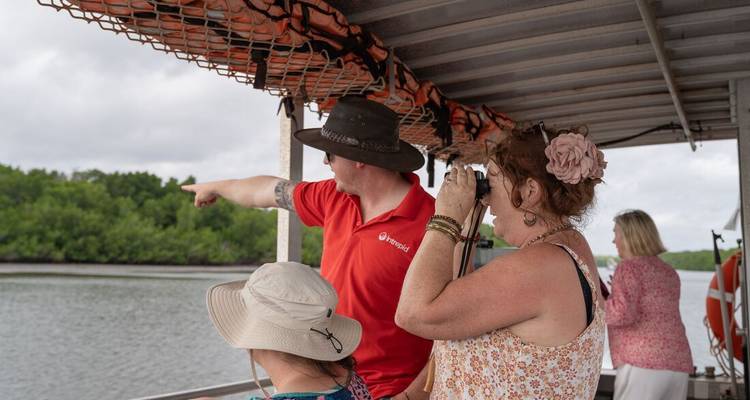 Des gens sur un bateau pointant vers quelque chose sur une voie navigable.
