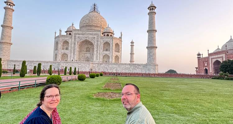 Couple assis sur la pelouse avec le Taj Mahal au loin.