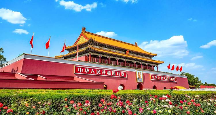 Puerta de Tiananmen con muros rojos, retrato de Mao y banderas chinas enmarcados por rosas en flor en Pekín.