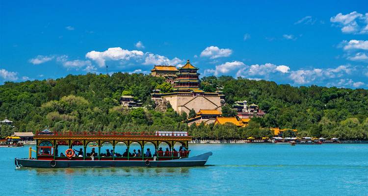 Bote de placer en el Lago Kunming con los templos en la cima de la Colina del Palacio de Verano de fondo bajo un cielo azul.
