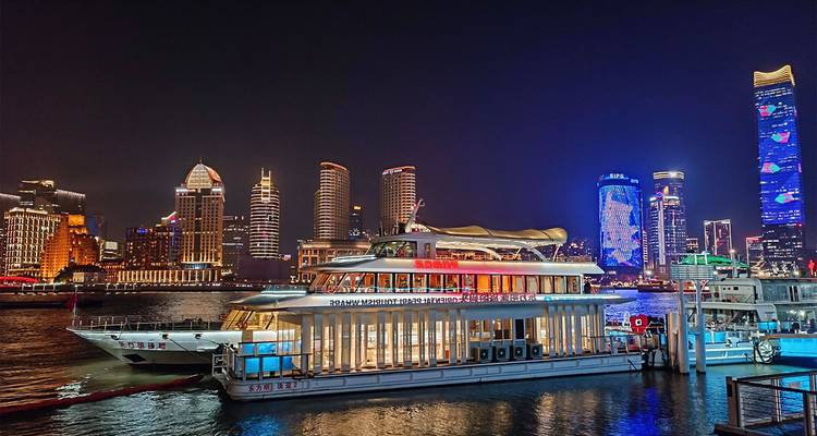 Cruceros nocturnos por el río Huangpu con el horizonte iluminado de Pudong y rascacielos coloridos en Shanghai.