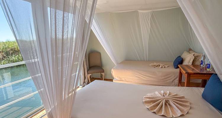 Interior of a cabin with two beds and net curtains on a houseboat.