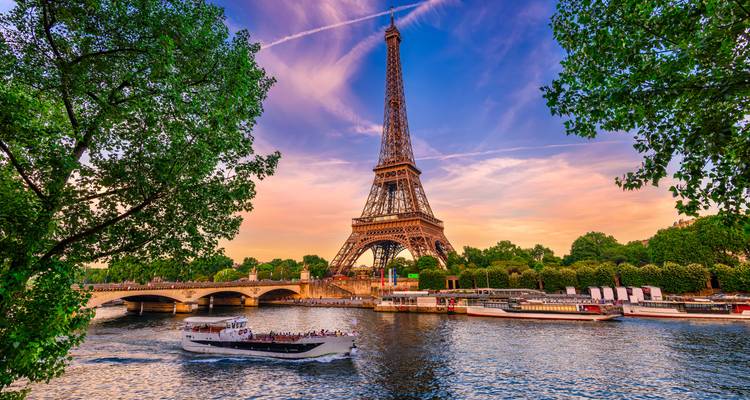 Tour Eiffel au coucher du soleil avec un bateau naviguant sur la Seine.