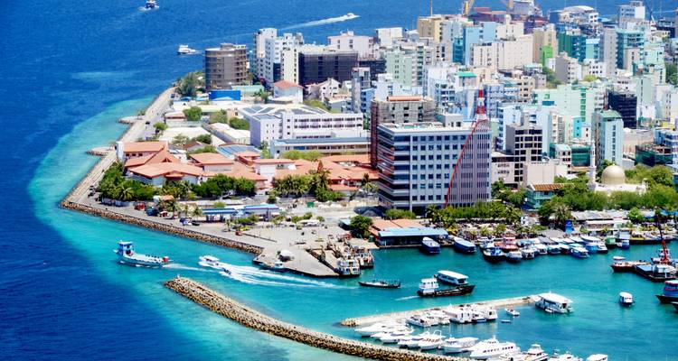 Vue aérienne d'une ville sur une île avec des bateaux et des eaux turquoise.