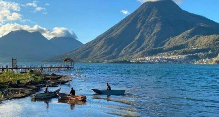 Schöner See mit Booten und Bergen im Hintergrund.