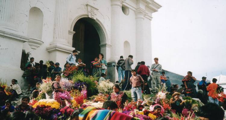 Gruppen von Menschen versammelten sich mit bunten Blumen vor einer Kirche.