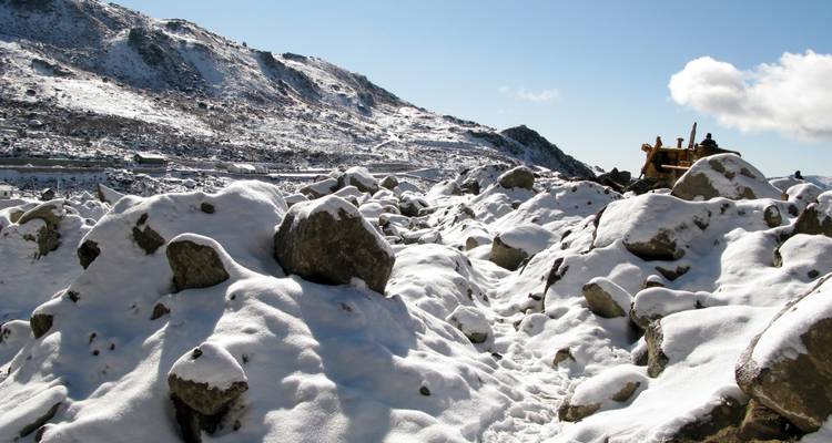 Snow-covered rocky landscape with clear blue sky.